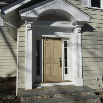 Photo of an entry way to a house. The house has beige color siding.